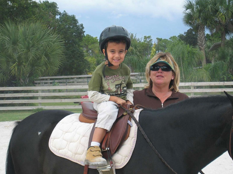 Donice Muccio standing next to young boy on horseback